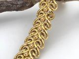 a close up of a gold bracelet on a branch of a tree