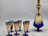 five glasses and a decanter sitting on a table
