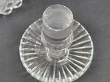 a glass candle holder on the table next to a glass vase