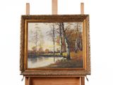 painting on easel of a landscape with a river and trees