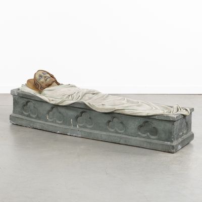 statue of a woman laying on a stone slab with a blanket on it