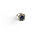 an image of a ring with a blue stone surrounded by diamonds