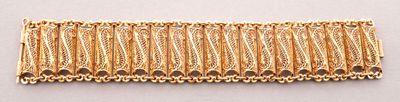 un gros plan d'un bracelet plaqué or sur une surface blanche