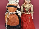 two dolls are standing next to each other on a pink background