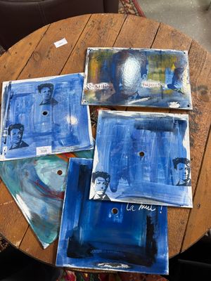 a wooden table topped with paintings on top of a wooden table