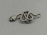 un gros plan d'une broche en forme de serpent posée sur une surface grise