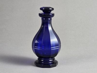 un vase en verre bleu avec un socle noir posé sur une surface grise