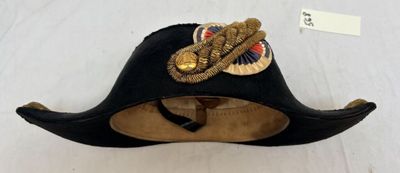 chapeau de pirate noir orné d'une bordure dorée et d'une plume sur le dessus