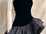 Le mannequin porte une robe noire et blanche ornée de volants.