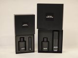 two black boxes with perfume bottles in them on a white surface