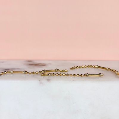 a close up of a gold chain bracelet on a marble surface
