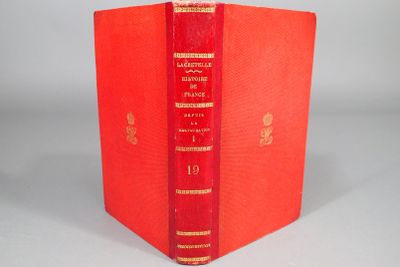 un livre orange à la couverture rouge posé sur une table blanche