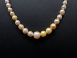 a pearl necklace with a yellow bead on a mannequin