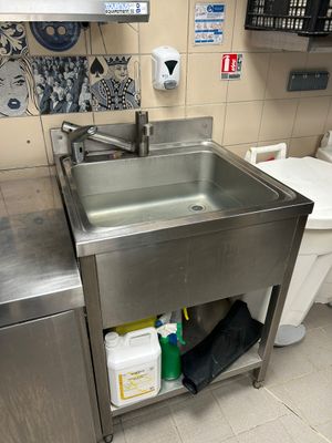 un évier en acier inoxydable dans le coin d'une toilette publique