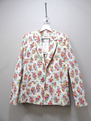 a white floral jacket hanging on a hanger on a wall