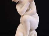 statue of a woman sitting on a white pedestal with a black background