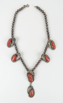 un collier composé de perles rouges et d'argent sur fond blanc