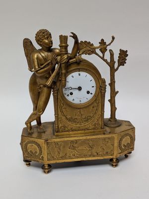 a gold clock with an angel on top of it