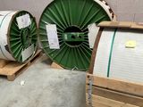 trois rouleaux de fil métallique vert et blanc posés sur des palettes dans un entrepôt