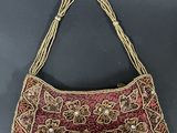 a red and gold embroidered purse on a black surface