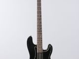a black electric bass guitar hanging from a white wall