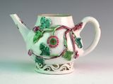 a white teapot with green and pink flowers on it