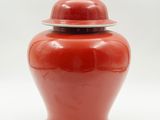 une image représentant un vase rouge muni d'un couvercle, sur fond blanc