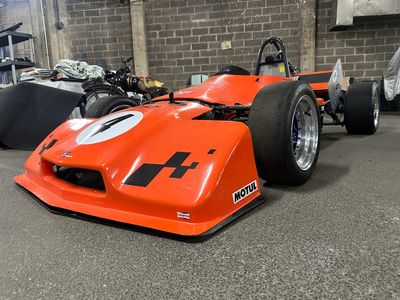 an orange race car that is parked in a garage