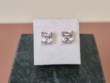 a pair of earrings sitting on top of a marble block