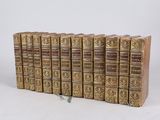 six vieux livres sont empilés sur une surface blanche