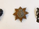 trois plaques métalliques sur un mur blanc, représentant un soleil et un aigle