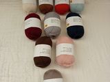 many balls of yarn sitting on a bed next to each other