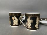 two black and gold coffee cups sitting on top of a table