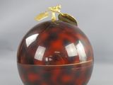 une pomme rouge surmontée d'une feuille d'or
