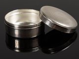 a silver container with a lid sitting on a black surface