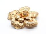 gold tone flower brooch with a center of petals on a white background
