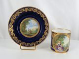 a close up of a cup and saucer with a painting on it