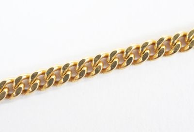 a close up of a gold chain bracelet on a white surface