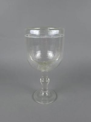 un verre à pied en verre transparent sur fond gris
