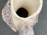 a small white vase with a hole in the middle