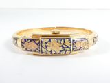 a close up of a gold and blue bracelet on a white surface