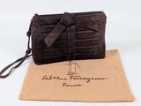 the brown purse is sitting on a tan bag with a brown ribbon around it