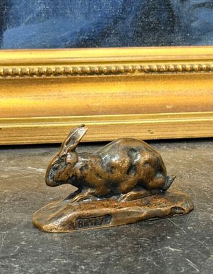 une sculpture en bronze représentant un lapin assis sur un rocher