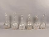 six vases en verre sont alignés sur une surface blanche