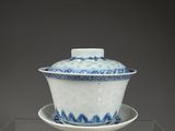 un bol et une soucoupe en porcelaine bleue et blanche posés sur une étagère transparente