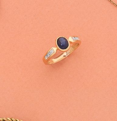 gros plan d'une bague en or avec un saphir et des diamants