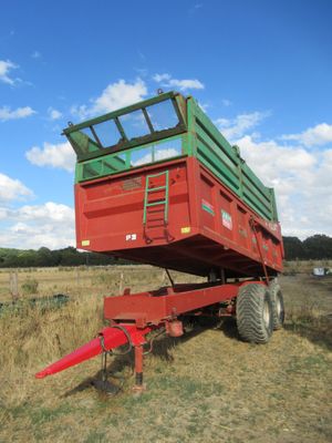 a red trailer with a green top parked in a field