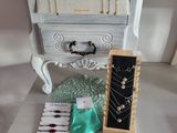 a white dresser with jewelry on it on a table