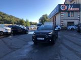 une voiture noire garée devant un bâtiment dans un parking