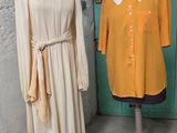 deux mannequins devant une porte verte et une robe posée sur un pied de mannequin